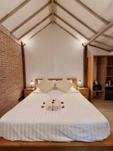 a bedroom with a white bed with roses on it at Kalua Boutique Bungalows in Gili Trawangan +47 photos