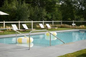 a swimming pool with white lounge chairs and a swimming pool at The Litchfield Inn in Litchfield