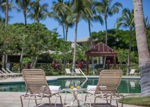 two chairs and a table in front of a pool at Mauna Lani Fairways 903 in Waikoloa