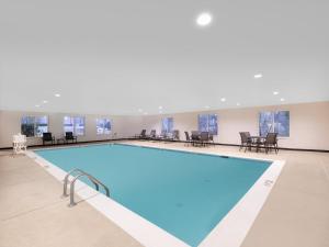 a large swimming pool in a building with tables and chairs at Garner Hotel Macon West by IHG in Macon