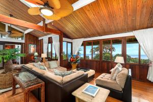 a living room with two couches and a ceiling fan at Orchid Hale in Kailua-Kona