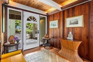 a living room with wood paneled walls and a door at Orchid Hale in Kailua-Kona