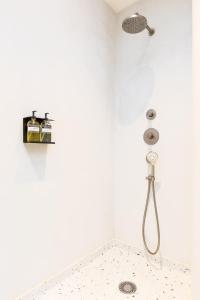 La salle de bains blanche est pourvue d'une douche avec un pommeau de douche. dans l'établissement Kith & Kin Boutique Apartments, à Amsterdam 60 autres photos