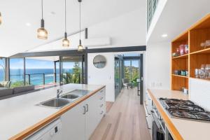 a kitchen with white counters and a view of the ocean at Sandcastle by Coast Hosting in Wamberal
