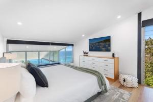 a bedroom with a large white bed and a window at Sandcastle by Coast Hosting in Wamberal +15 photos