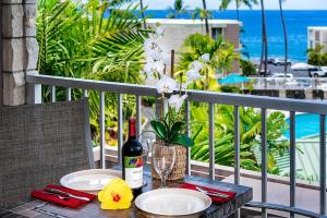 a table with plates and a bottle of wine on a balcony at Alii Villas 309 in Kailua-Kona