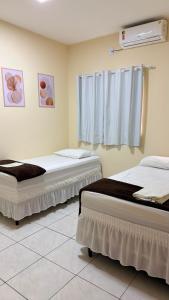 two beds in a room with a window at Villas hotel in Barreiras