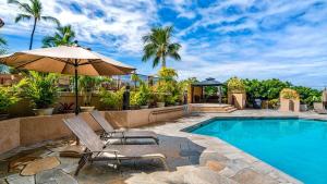 a swimming pool with two chairs and an umbrella at Kona Pacific C520. in Kailua-Kona