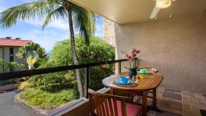 a table and chairs on a balcony with palm trees at Kona Pacific C520. in Kailua-Kona