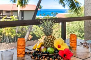 a pineapple and other fruits on a table on a balcony at Kona Pacific D622 in Kailua-Kona