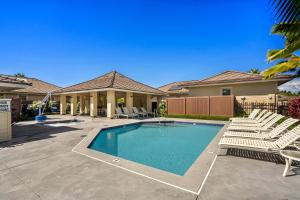 a swimming pool with chairs and a house at Holua Kai 37 in Kailua-Kona