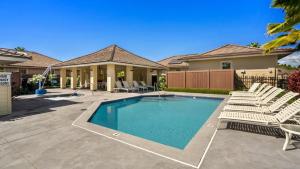 a swimming pool with chairs and a house at Holua Kai 6 in Kailua-Kona