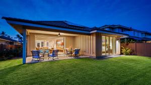a house with chairs and a table on a lawn at Holua Kai 6 in Kailua-Kona