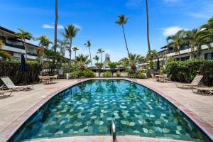 a swimming pool at a resort with chairs and palm trees at Casa de Emdeko 124 in Kailua-Kona