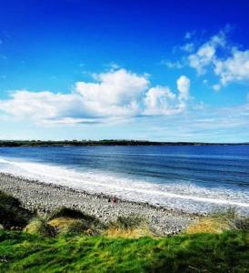 a beach with water and a blue sky and clouds at Double room with ensuite in Milltown Malbay
