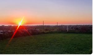 a sunset over a field with a rainbow in the sky at Double room with ensuite in Milltown Malbay