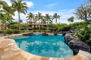 a swimming pool in front of a resort with palm trees at Waikoloa Beach Villas L3 in Waikoloa