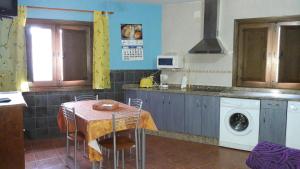 a kitchen with a table and a washing machine at Apartamentos Alejandra in Gargantilla