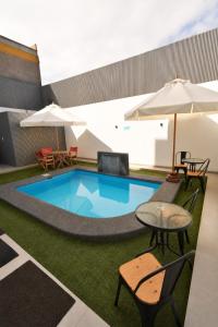 a pool with tables and chairs and umbrellas at Apart Hotel Regata Iquique in Iquique