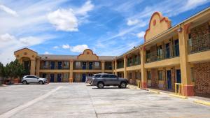 a large building with cars parked in a parking lot at Deluxe Inn By Capital O Odessa I-20 in Odessa