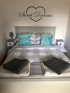 a bed with blue pillows and a sign that reads queen dreams at Our Wendy House in Holsworthy +5 photos