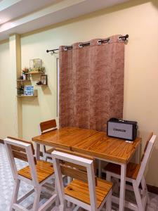 a dining room table with chairs and a curtain at เพียงภูโฮมสเตย์ in Sattahip
