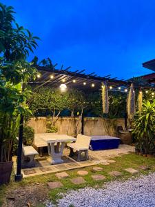 a picnic table and bench under a pergola at night at เพียงภูโฮมสเตย์ in Sattahip
