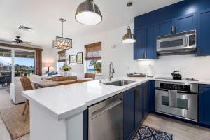 a kitchen with blue cabinets and a living room at Halii Kai 11D in Waikoloa