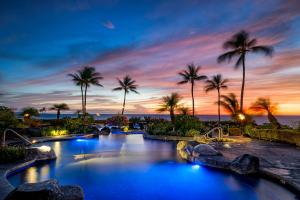 a resort pool with palm trees at sunset at Halii Kai 11D in Waikoloa