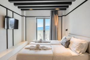 two beds in a room with a large window at Veneto Sea View Apartments in Stalís