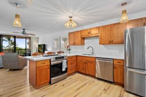 a kitchen with wooden cabinets and stainless steel appliances at Kona Pacific A306 in Kailua-Kona