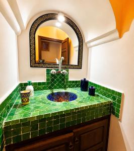 a green tile bathroom with a sink and a mirror at Villa Jardin De l'Ocean in Aourir