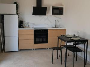 a kitchen with a black table and a white refrigerator at Studios Saint Mau 1 in Saint-Maurice-de-Gourdans