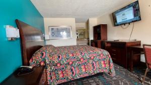 a hotel room with a bed and a flat screen tv at Deluxe Inn By Capital O Odessa I-20 in Odessa