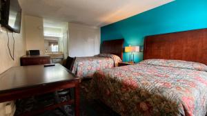 a hotel room with two beds and a blue wall at Deluxe Inn By Capital O Odessa I-20 in Odessa