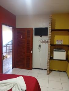 a bedroom with a bed and a tv and a door at Pousada Sena in Flecheiras