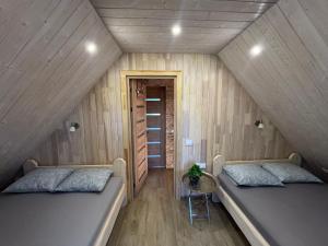 two beds in a room with wooden walls at Pakarklių sodyba in Anykščiai