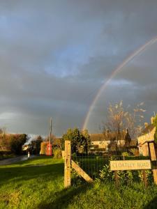 a rainbow over a field with a fence and a sign at Brookfield in Malmesbury