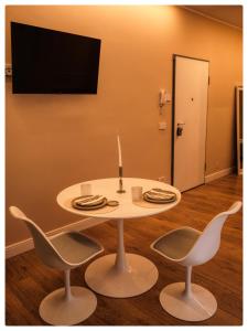 a white table with two chairs and a television on a wall at Adapartament in Vercelli