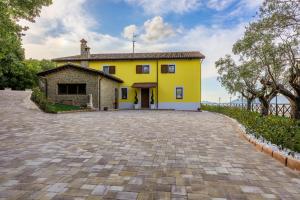 a yellow house with a brick driveway at Villa Paradiso in Pioraco