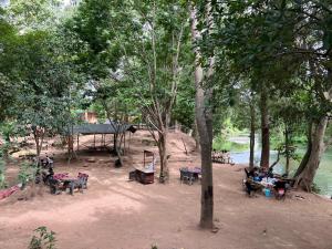 a group of people sitting at picnic tables near a river at เป้แคมป์ปิ้งเขาใหญ่ in Ban Khanong Phra Tai