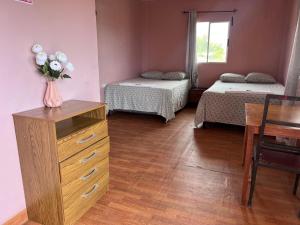 a room with two beds and a vase of flowers on a dresser at Hotel Atlántida in La Ceiba