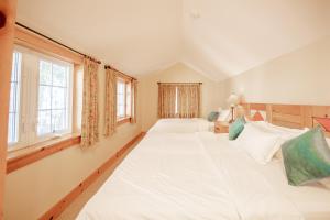 two large white beds in a room with windows at Lakefront Cottage Private Beach & & Kayaks in Georgina +30 photos