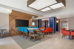 a dining room with tables and chairs and a flat screen tv at Holiday Inn Express Deforest Madison Area by IHG in De Forest
