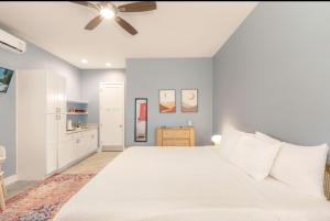 a bedroom with a white bed and a ceiling fan at Sunny Side Cottages in Dunedin +52 photos