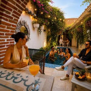 a group of people sitting around a pool with drinks at Casa Heredia Boutique in Cartagena de Indias