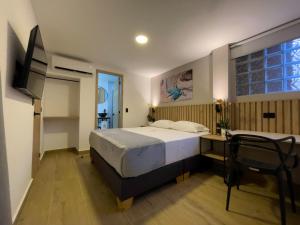 a bedroom with a bed and a desk and a window at Vita Hotel Boutique - Aire Acondicionado & Desayuno in Medellín