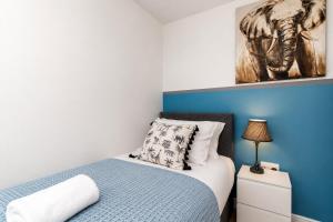 a bedroom with a bed with a blue accent wall at Large 3 bed Double Driveway Smart TVLong Stays in Durham