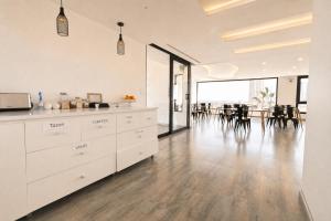 a kitchen with white cabinets and a dining room with a table at Apart Hotel Regata Iquique in Iquique