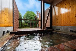a pool of water in a house with wooden walls at Okuyado Buaiso in Yufu
